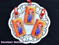 two key chains with pictures on them sitting on a doily