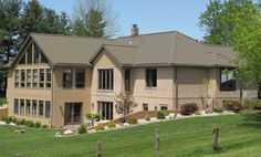 a large house sitting in the middle of a lush green field with lots of trees