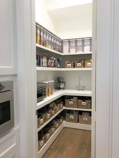 an organized pantry with white shelves and brown baskets on the bottom shelf, filled with food