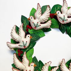 a wreath made out of paper with white doves and holly leaves on the front