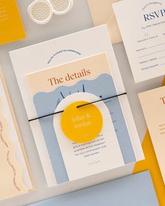 the wedding stationery is laid out on top of each other, including an orange and blue button