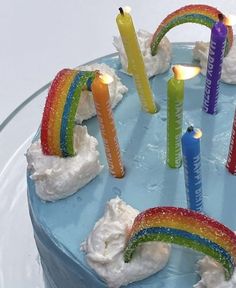 a cake decorated with candles and rainbows on top of a blue plate, ready to be eaten