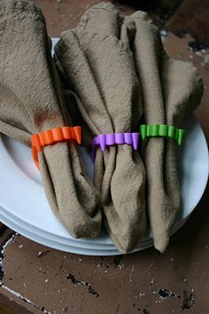 three pieces of cloth sitting on top of a white plate with orange and purple handles