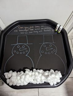 a black tray with marshmallows and two snowmen drawn on it