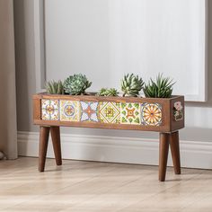 two succulents are sitting in a wooden planter on top of a table