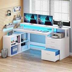 a computer desk with two monitors on top of it and drawers underneath the desk, in front of a window