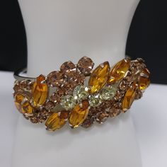 *Description: This is a gorgeous light and dark topaz & jonquil rhinestone hinged bracelet and matching earrings from the 1960s. This jewelry is designed in the Julianna style with hinged rhinestone bracelet and clip earrings. The back of the bracelet and earrings, behind the rhinestones, are gold plated. The set is not signed but is obviously a designer set due to the style and quality settings. This would be a great addition to your vintage jewelry collection or make a great vintage gift! Retro Orange Jewelry For Party, Vintage Orange Jewelry For Party, Formal Yellow Jeweled Jewelry, Retro Party Bangle Jewelry, Vintage Amber Jewelry For Party, Vintage Brown Bracelets For Party, Hinged Bracelet, Rhinestone Bracelet, Gorgeous Bracelet