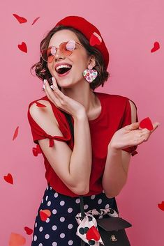 a woman in red shirt and polka dot skirt holding a cell phone to her ear