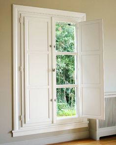 an empty room with a large window and white cupboards in front of the window