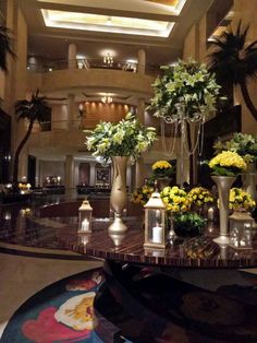 flowers and candles in vases on a table at a hotel lobby reception area with chandelier