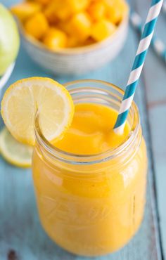 a mason jar filled with orange juice and topped with a blue striped straw