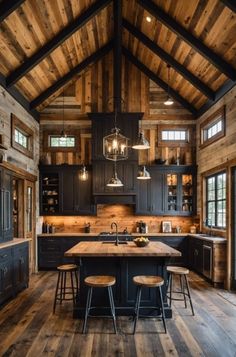 a large kitchen with wooden floors and black cabinets, an island countertop and stools