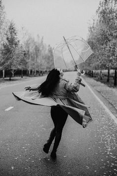 a woman is running down the street with an umbrella in her hand and she has long black hair