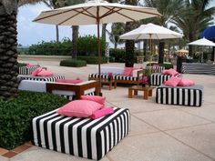 black and white striped couches with pink pillows under umbrellas at an outdoor restaurant