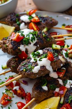 lamb skewers with tomatoes, onions and herbs on a white plate