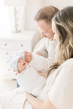 a man and woman holding a baby in their arms