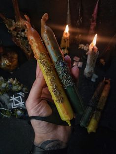 a person holding some kind of candle in their hand with other candles around them on the table