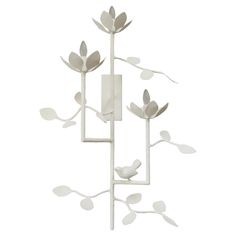 a white metal sculpture with flowers and leaves on it's sides, against a white background