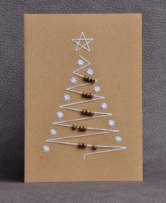 a christmas tree made out of pins on a brown card with white snowflakes