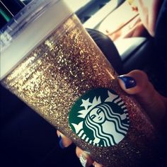 a woman holding a starbucks cup in her hand with the caption, diy glitter starbucks cups sprayed the inside of the outer cup w