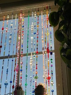 a window with beads hanging from it and a potted plant next to the window