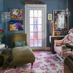 a living room filled with furniture and paintings on the wall behind a glass front door