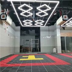 the inside of an empty building with red and yellow floor tiles on the floor, lights hanging from the ceiling