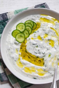 a white bowl filled with cucumber and ranch dressing on top of a checkered table cloth