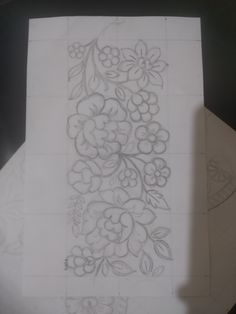 a piece of paper that has been drawn with flowers and leaves on it, sitting on top of a table