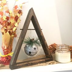 a wooden triangle with a potted plant in it and a candle next to it