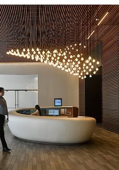 a woman standing in front of a counter with lights hanging from it's ceiling