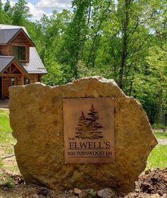 a large rock sitting in front of a house with a sign on it that says elwell's