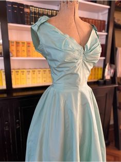 "A gorgeous gown made from tissue silk taffeta in a tiffani blue colour.  The dress was made by Hardy Amies in 1963 for a debutante attending the royal wedding of Princess Alexandra and Sir Ian Ogilvy.  It comes direct from the owner (via an auction house) who included a photo of the invitation to the wedding.  They did not wish to part with the actual invitation so it's just a photo. The dress is waisted with a full flared skirt lined in a stiff fabric for fullness.  Pleating at centre bust and bows at the shoulders.  It appears the wearer pinned the bows under the shoulders as they thought they were too wide.  There is a corset undergarment with padded bust. The dress is a size small and in excellent condition except for surface marks at the waist (see last photo) at the hemline, underar Silk Taffeta Dress, Stiff Fabric Dress, Corset Undergarment, Ian Ogilvy, Stiff Fabric, Taffeta Wedding Dress, Full Flared Skirt, Taffeta Gown, Hardy Amies