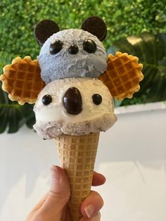 a hand holding an ice cream cone with mickey mouse on top and waffles in the shape of ears