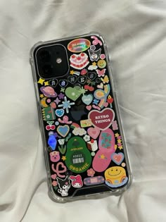 an iphone case with stickers on it sitting on a white sheet covered bedding