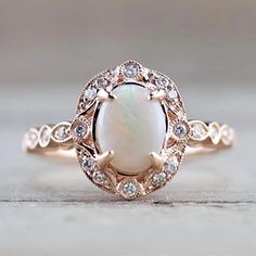 a white opal and diamond ring on top of a table