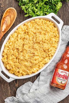 macaroni and cheese in a white casserole dish with a wooden spoon next to it