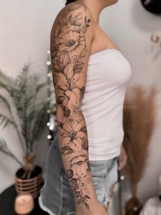 a woman with a flower tattoo on her arm is standing in front of a mirror