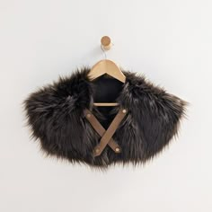 a fur coat hanging on a wall with a wooden hanger in front of it