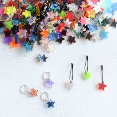 several different colored star shaped earrings on a white surface with one earring in the middle