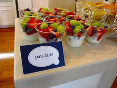 small cups filled with fruit and yogurt on top of a counter next to a sign that says parfaits