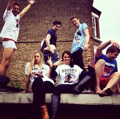 a group of young people sitting on top of a cement wall next to each other