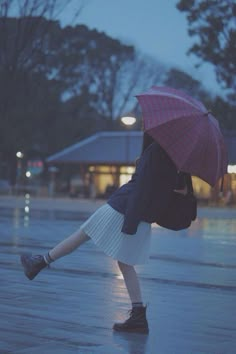 a woman is walking in the rain with an umbrella over her head and shoes on