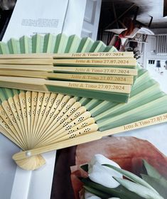 four wooden fans sitting on top of a table next to flowers and pictures with names