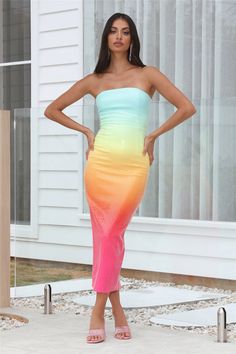 a woman standing in front of a house wearing a dress that is multicolored