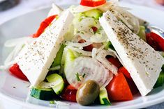 a salad with cucumbers, tomatoes, and olives on a white plate