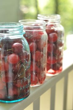 jars filled with cherries sitting on top of a table