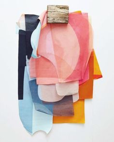 a piece of wood sticking out of a pile of different colored fabrics on a white wall