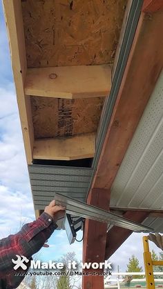 a man working on the side of a building with wood and metal beams attached to it