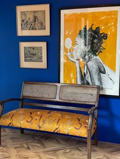 a bench sitting in front of a blue wall with pictures on the wall behind it